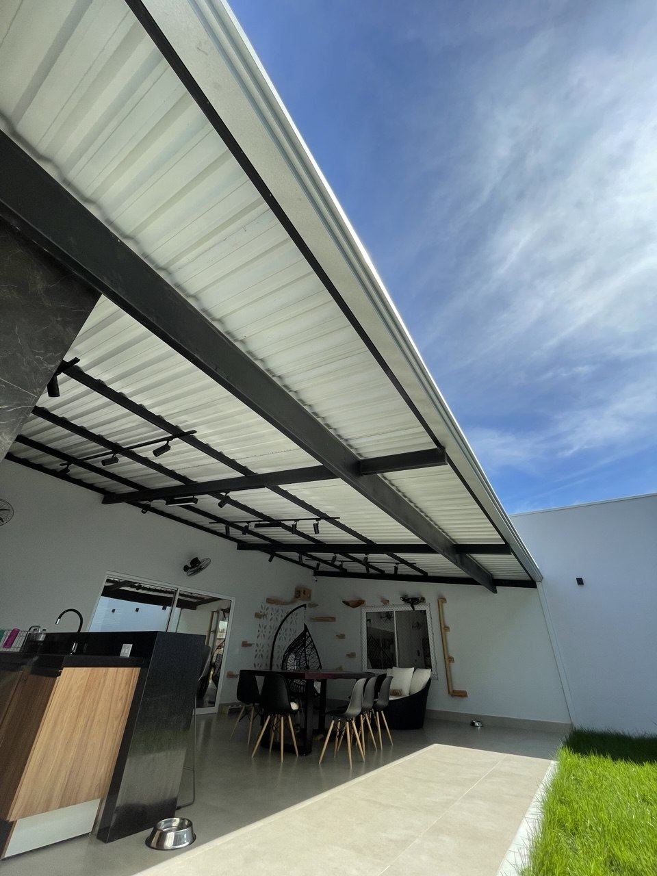 Área gourmet coberta com telha sanduíche pintada e estrutura metálica preta, em Vilhena